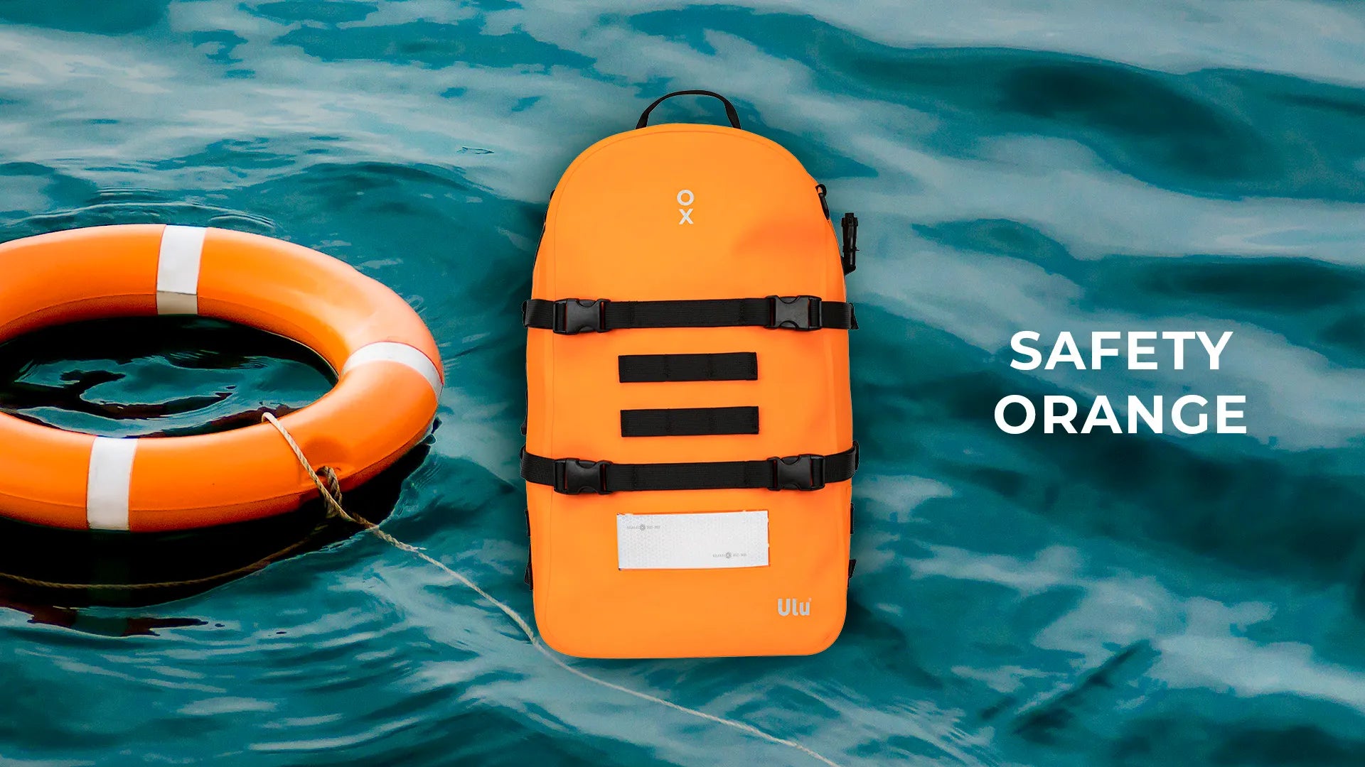 Ulu bag in orange over an image of the sea, next to an orange safety buoy